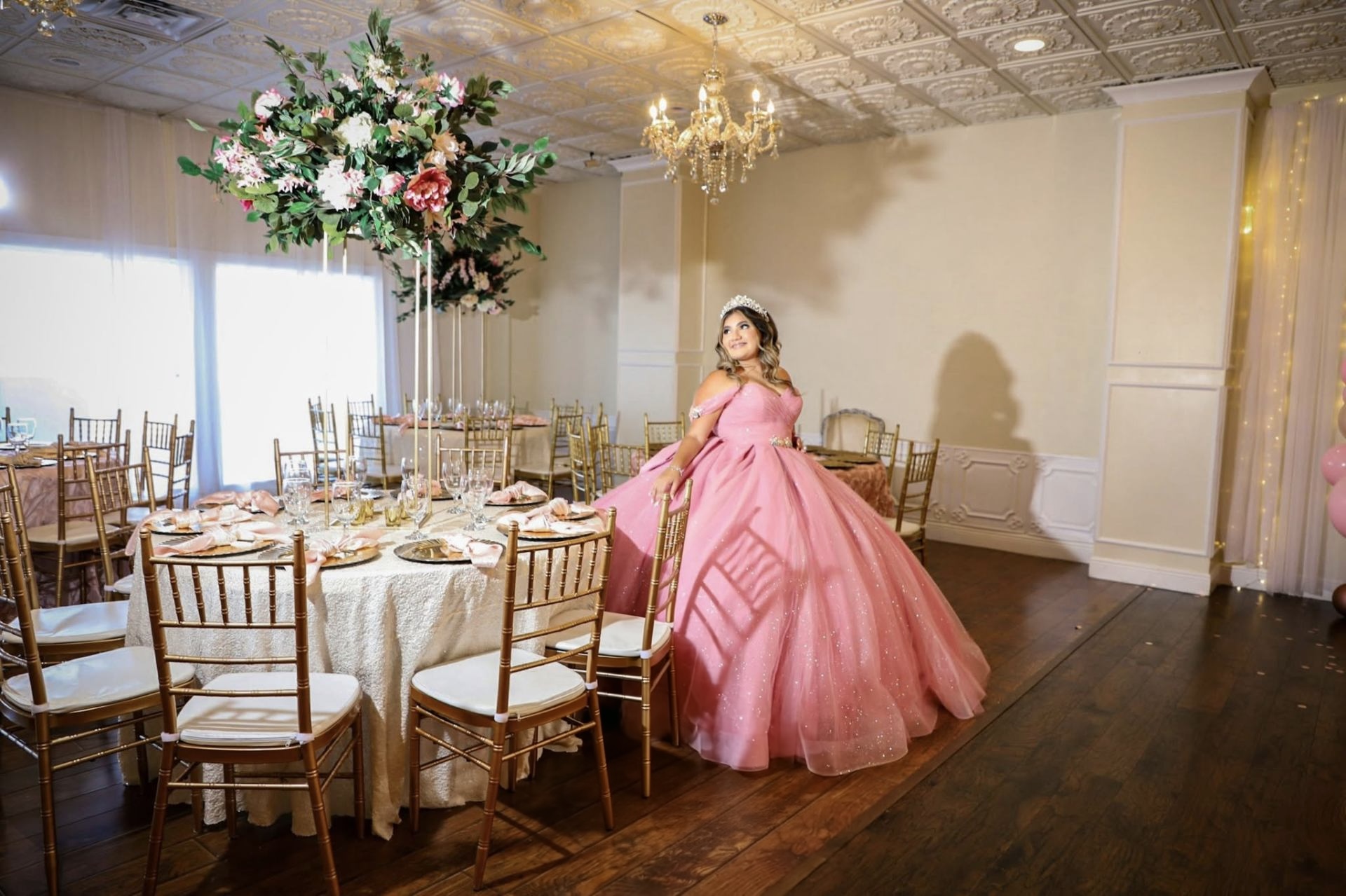 Quinceañera reception room with tall floral centerpieces and gold chiavari chairs