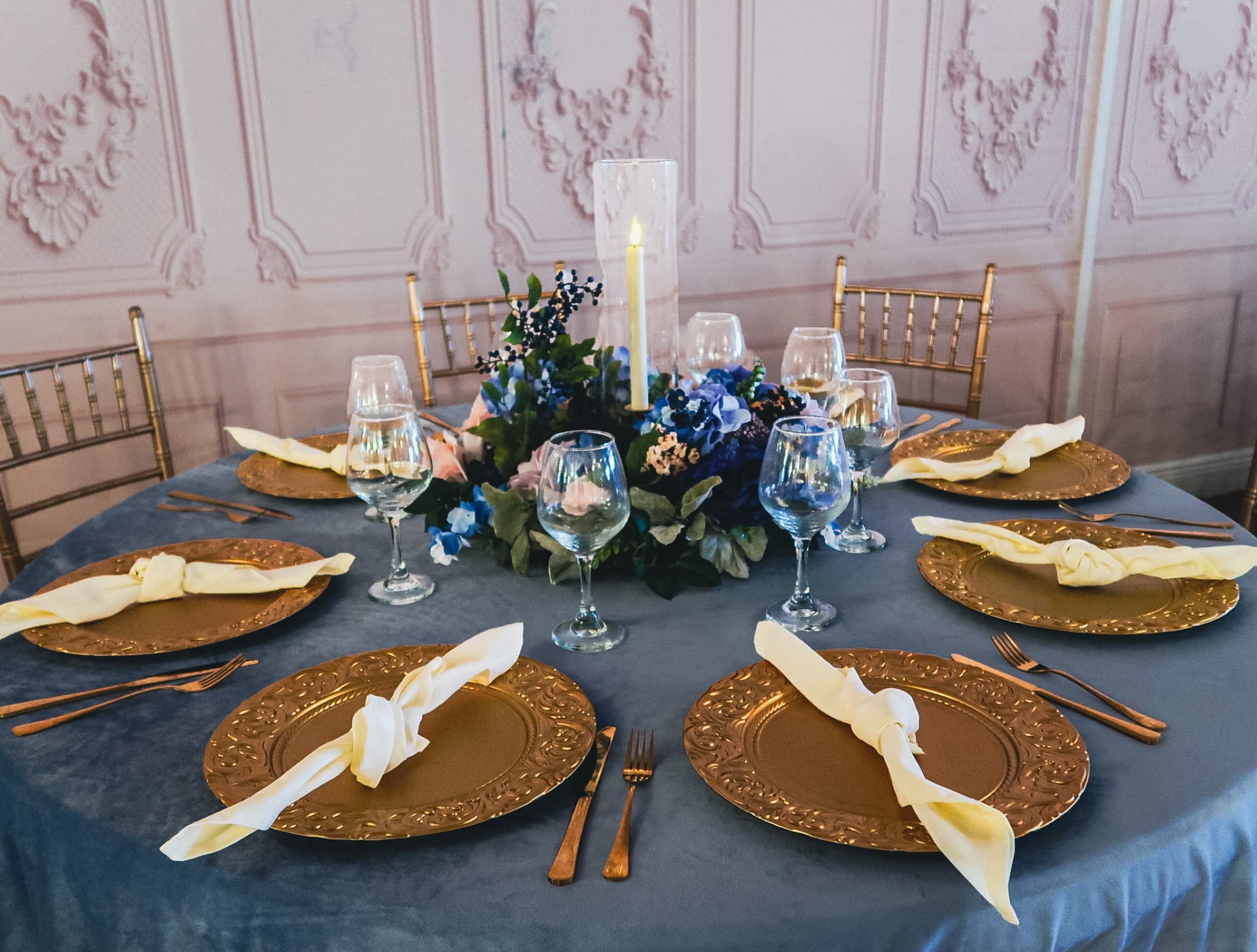 Dusty blue velvet table with gold chargers and a hydrangea centerpiece