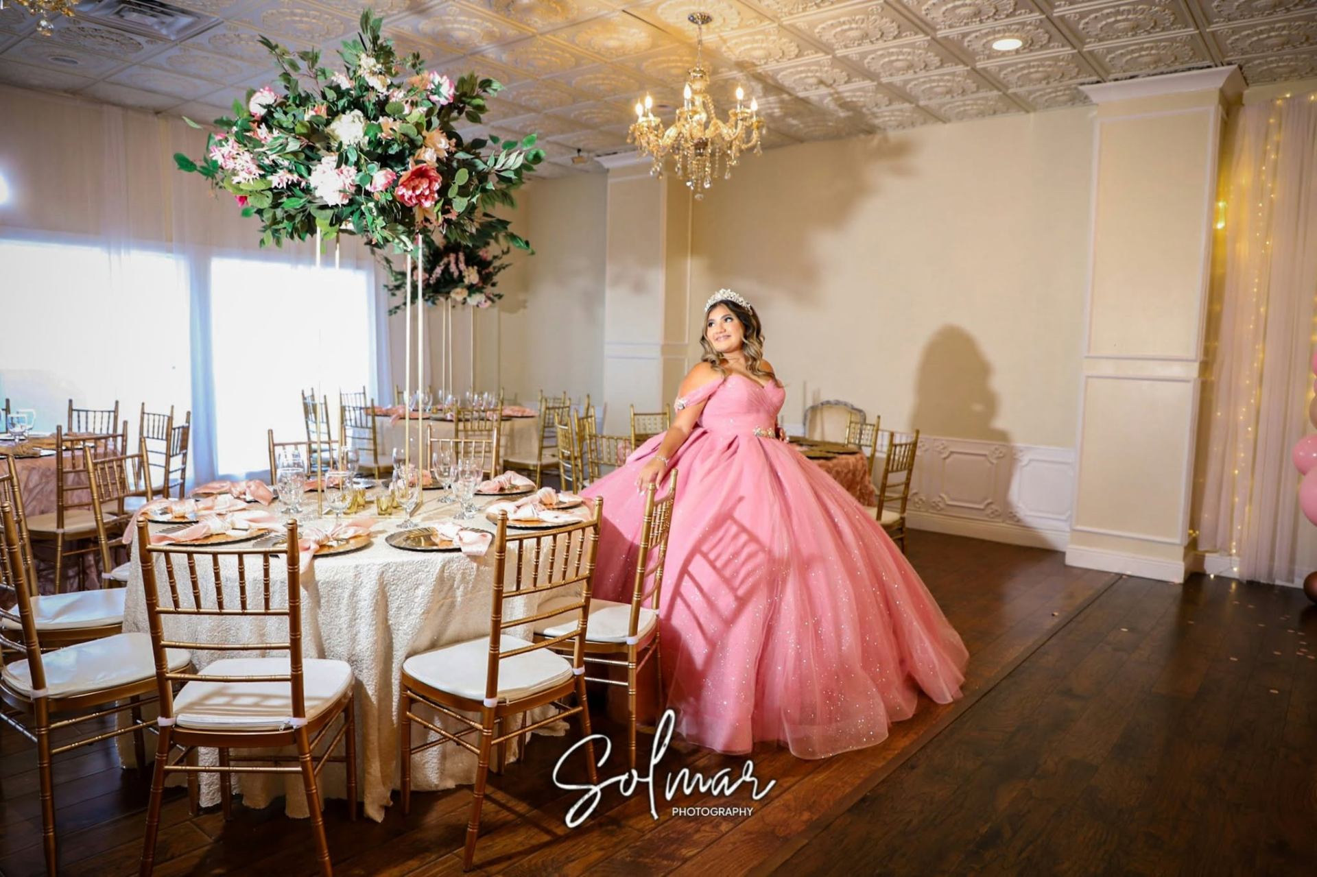 Quinceañera beside her reception table with tall floral centerpieces