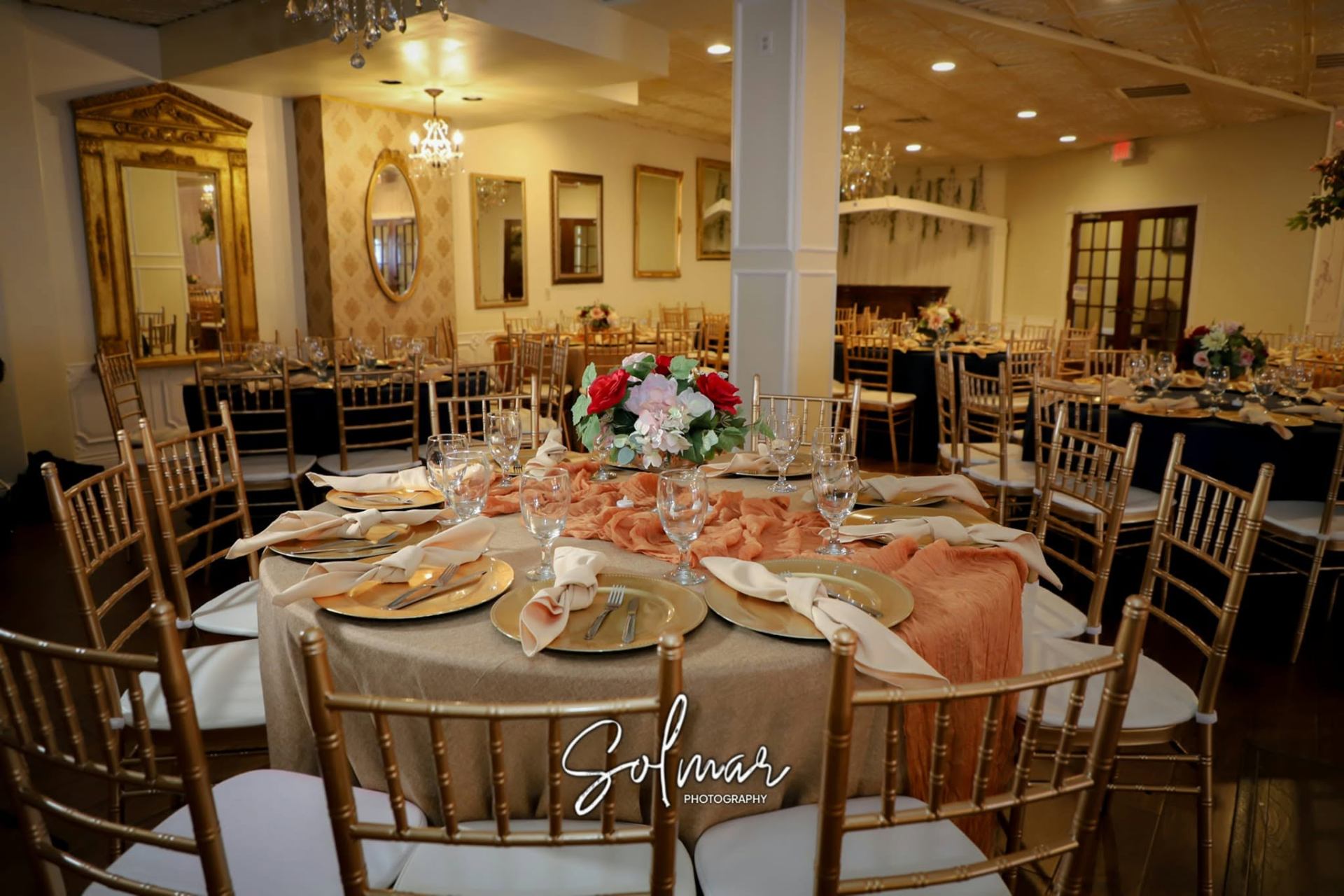 Wide view of the grand ballroom set with gold chiavari chairs and floral centerpieces