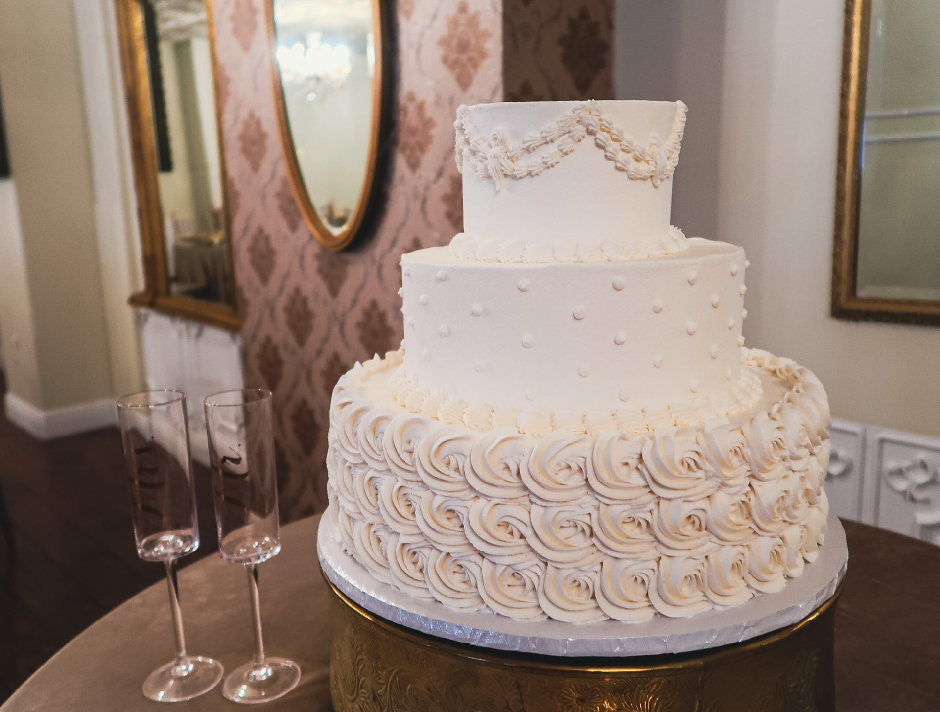 Three-tier white wedding cake with champagne flutes