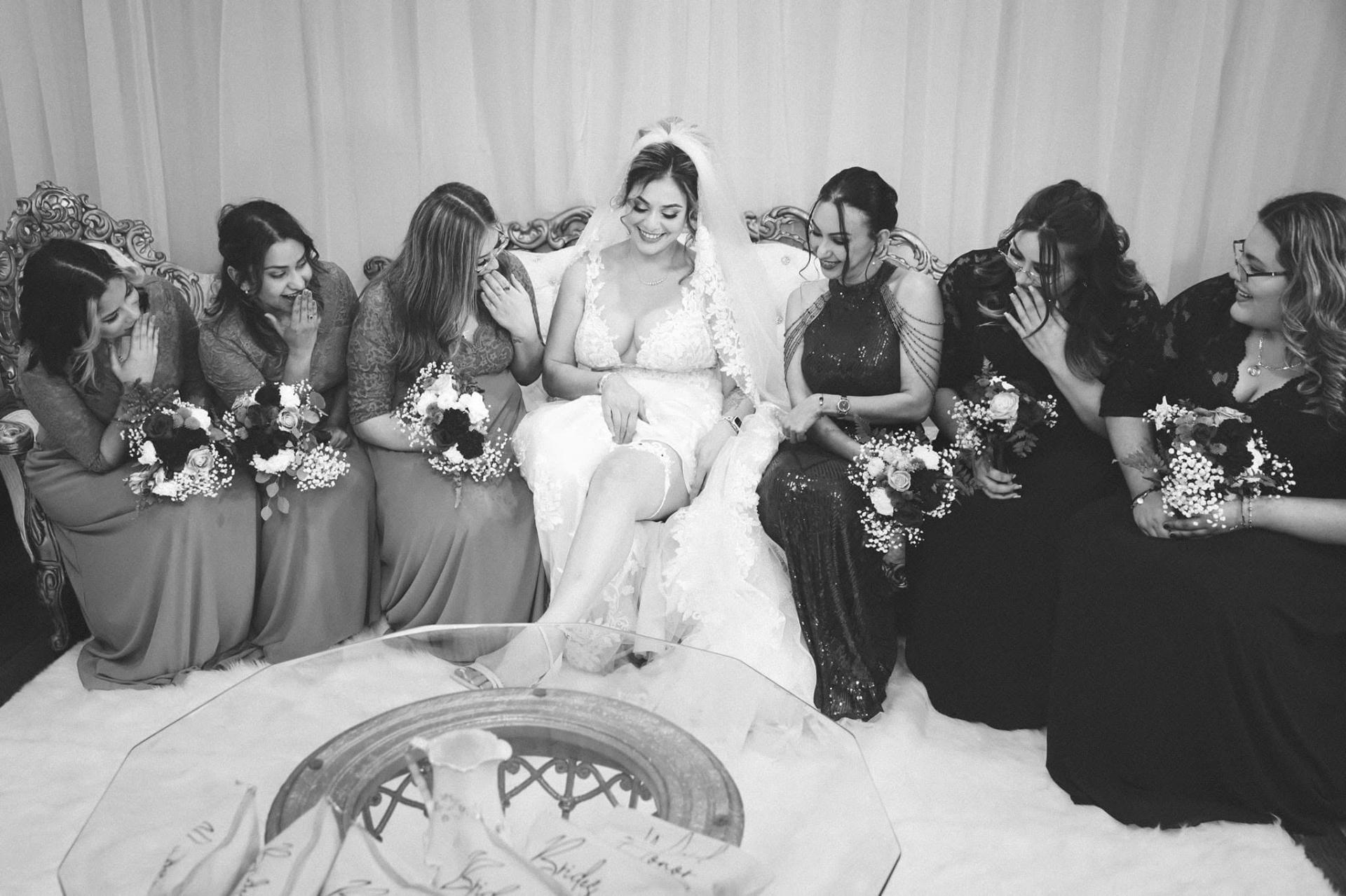Bride and bridesmaids laughing together on a vintage settee