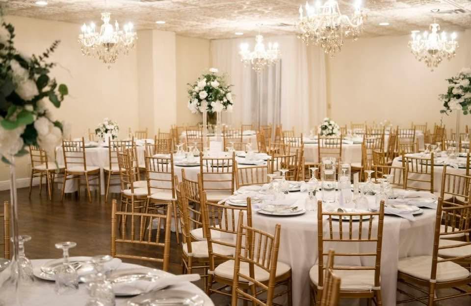 Wedding reception with chandeliers and tall florals