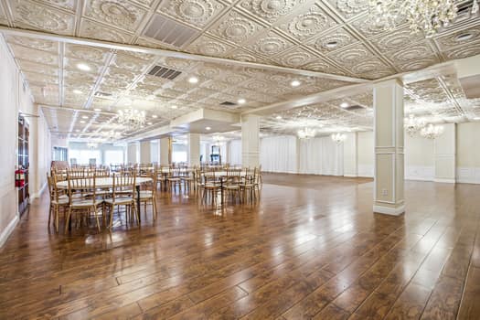 Grand venue with glossy wood floors, white columns, and round tables