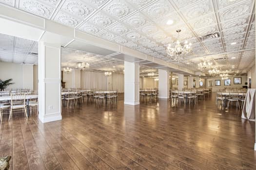 Grand venue banquet room with white columns and tin-style ceiling