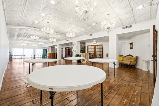 Small venue floor with round tables and a gold tufted settee in the alcove