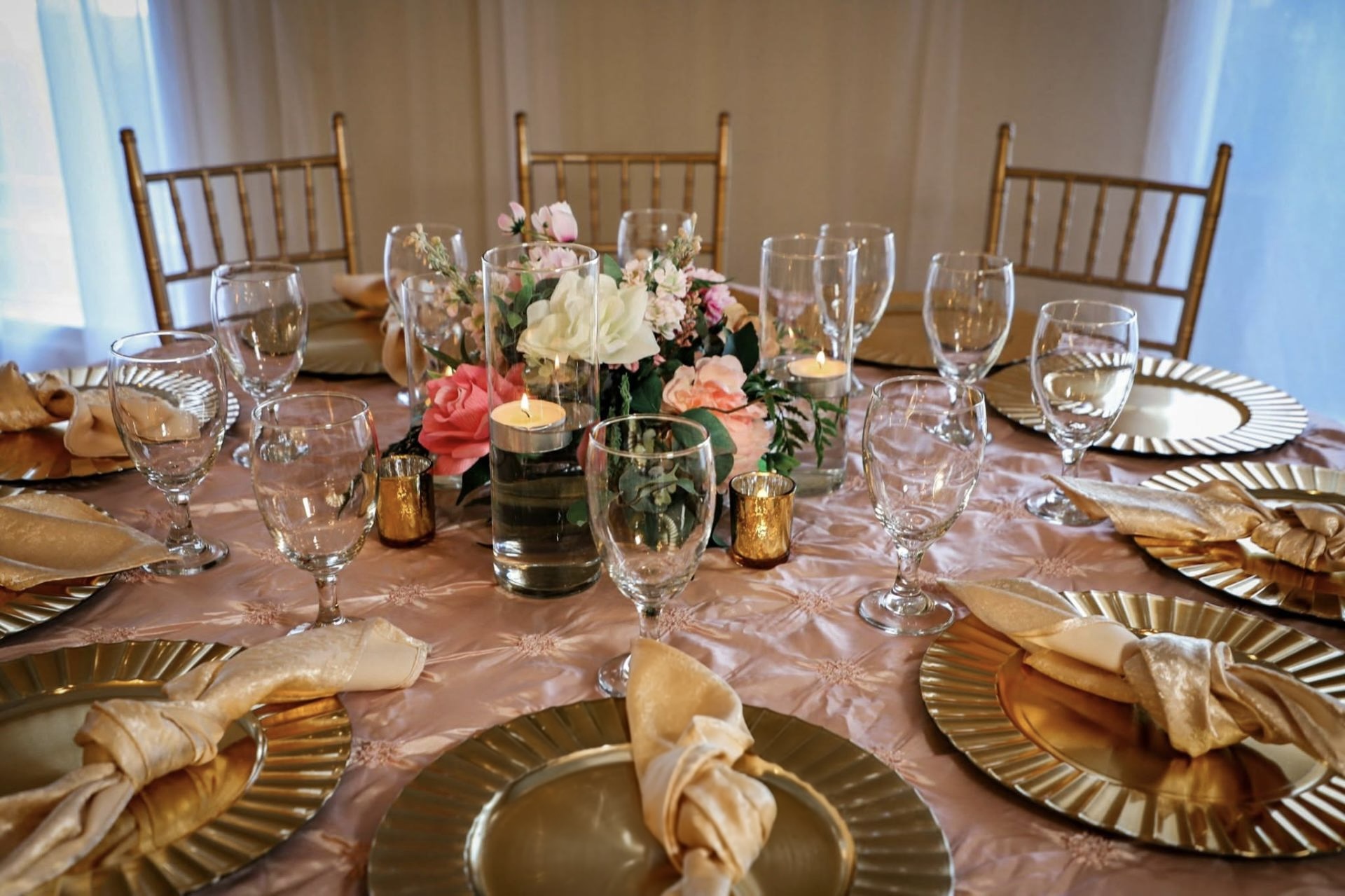 Blush tablescape with gold chargers, floating candles, and garden roses