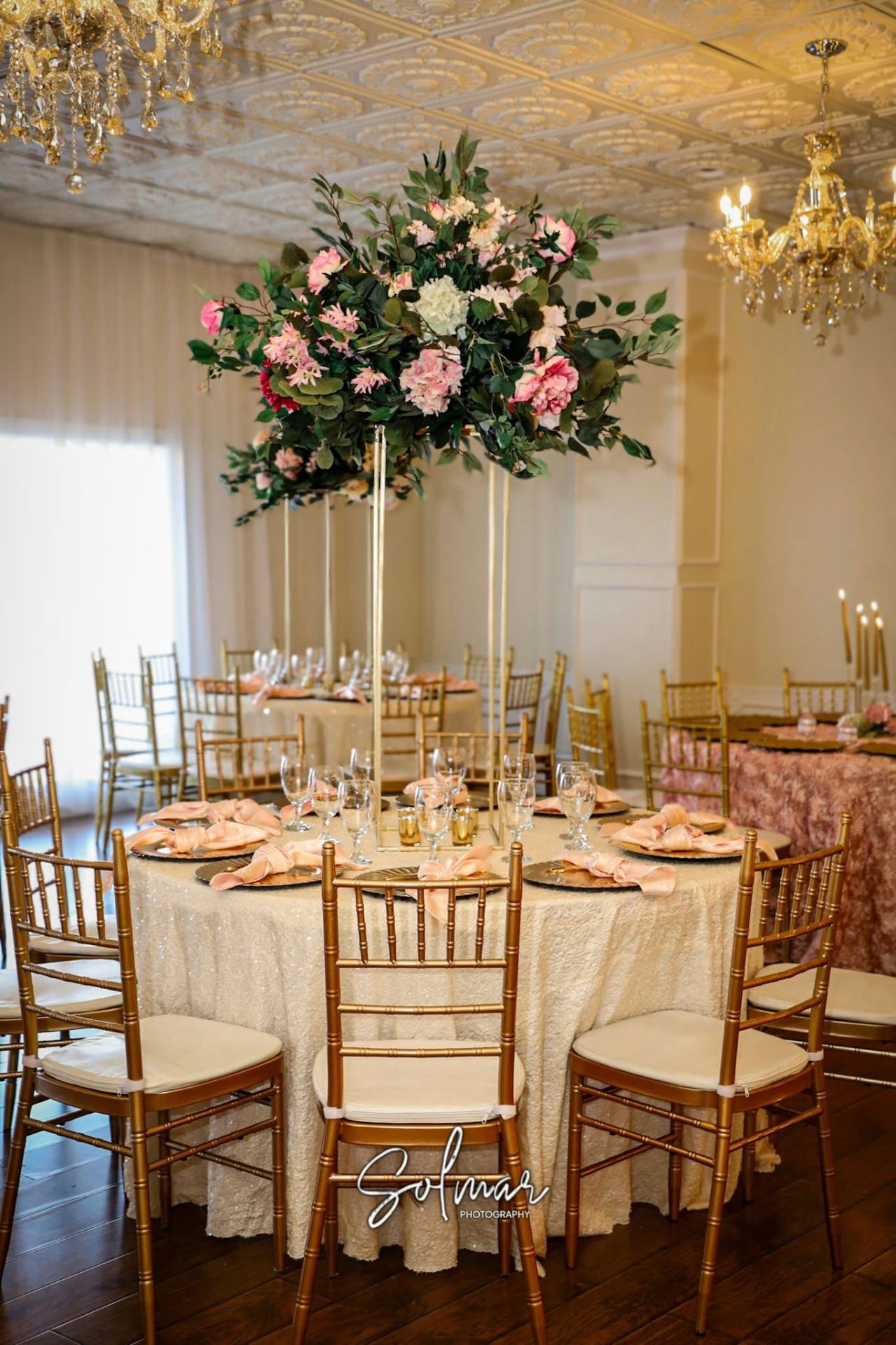 Tall pink and green floral centerpiece over a sequined tablescape